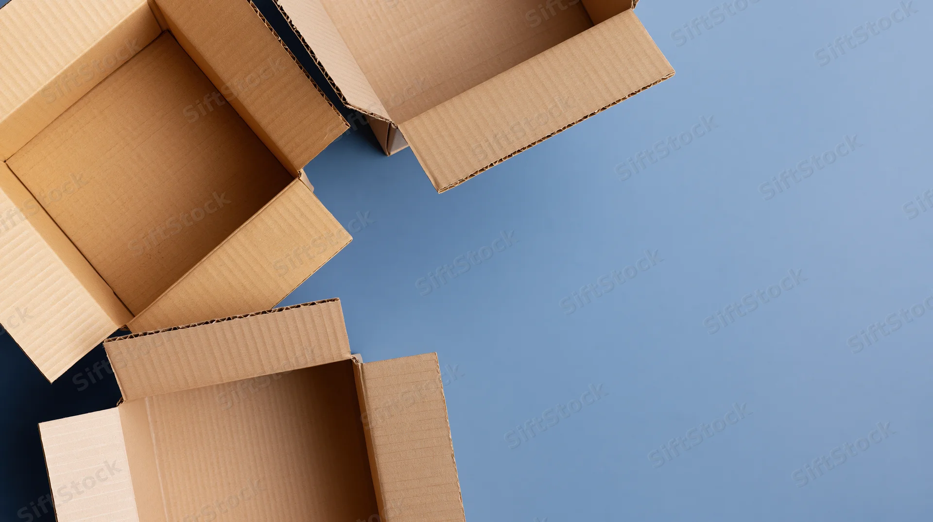 Open cardboard boxes arranged on a blue surface with copyspace