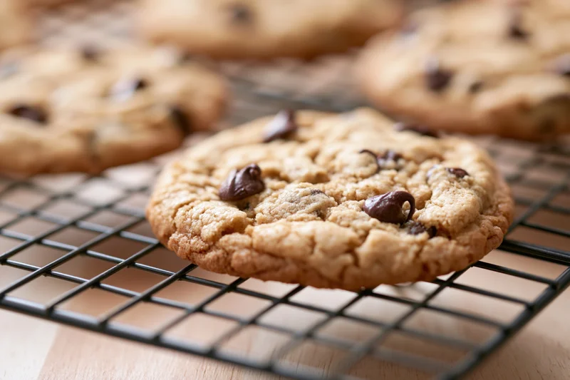 Chocolate chip cookies cooling on a wire rack in a kitchen