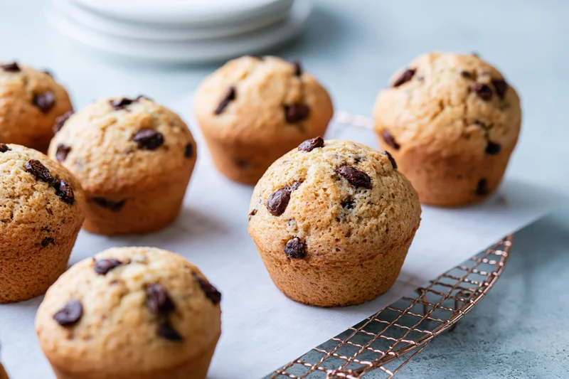Chocolate chip muffins cooling on a wire rack with parchment paper