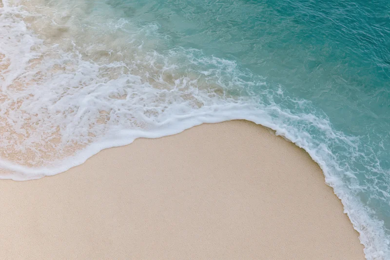 Gentle wave washing over sandy beach from above