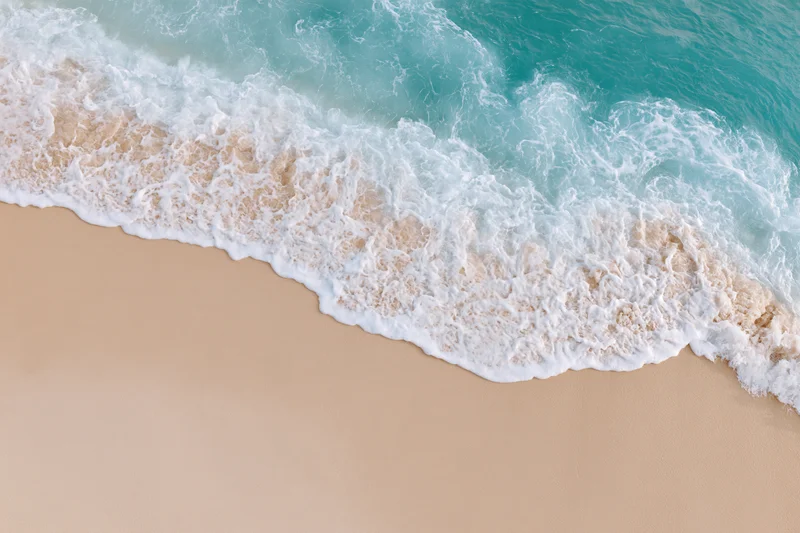 Turquoise ocean wave crashing onto sandy beach