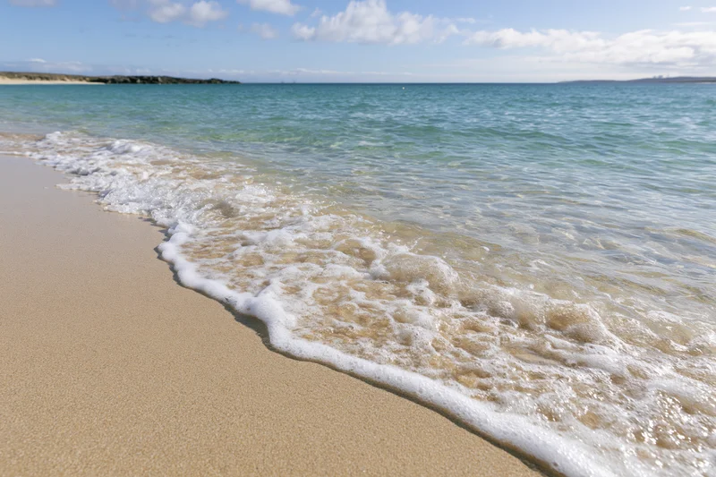 Gentle waves rolling onto sandy beach under clear sky