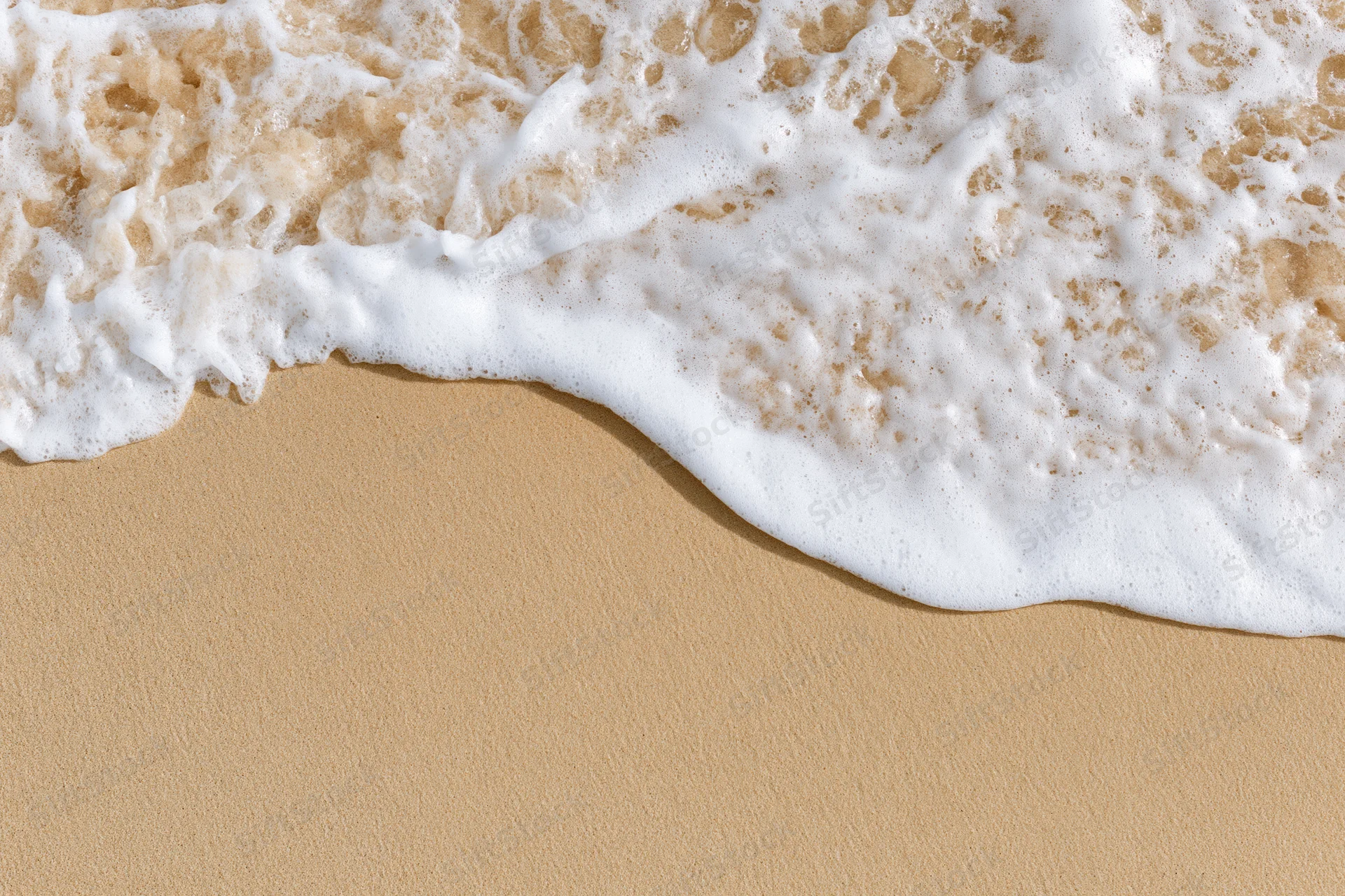 Ocean wave foam meeting sandy beach from above