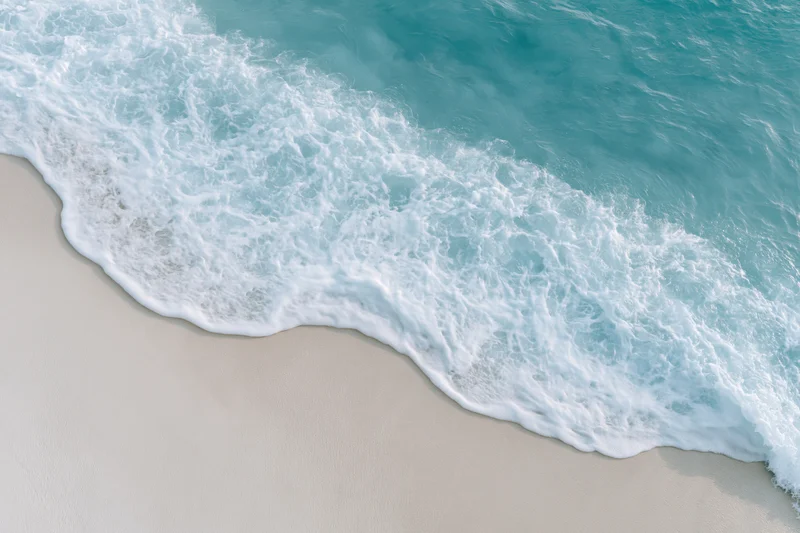 Turquoise ocean wave breaking onto white sandy beach