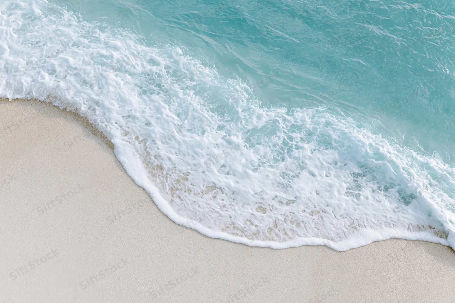 Turquoise ocean wave with white foam washing onto light sand beach