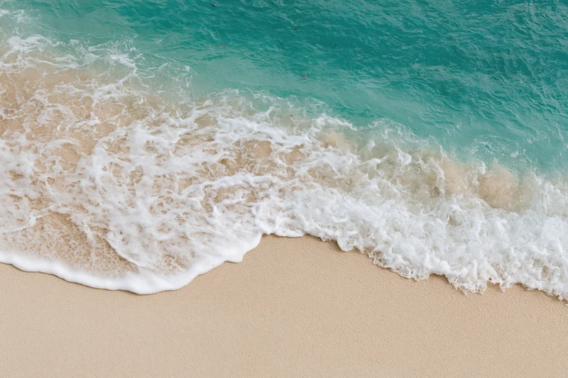 Turquoise ocean wave breaking onto sandy beach