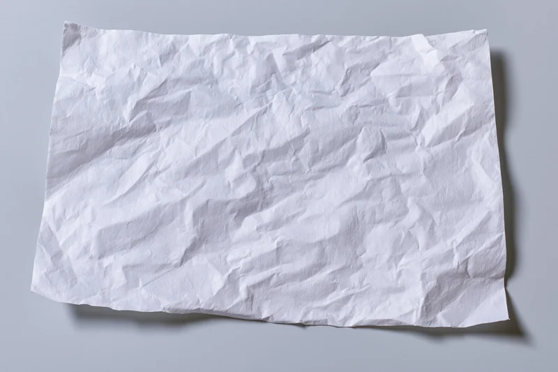 Crumpled white paper sheet lying flat on gray surface