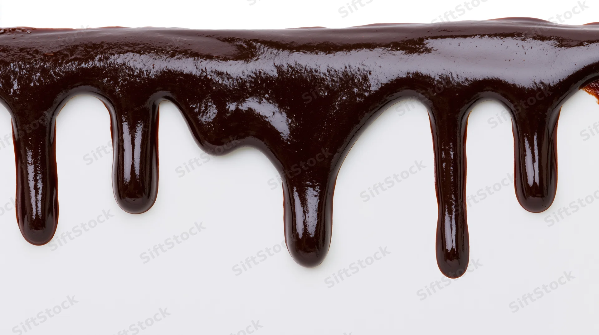 Chocolate sauce dripping in glossy streams against a white background