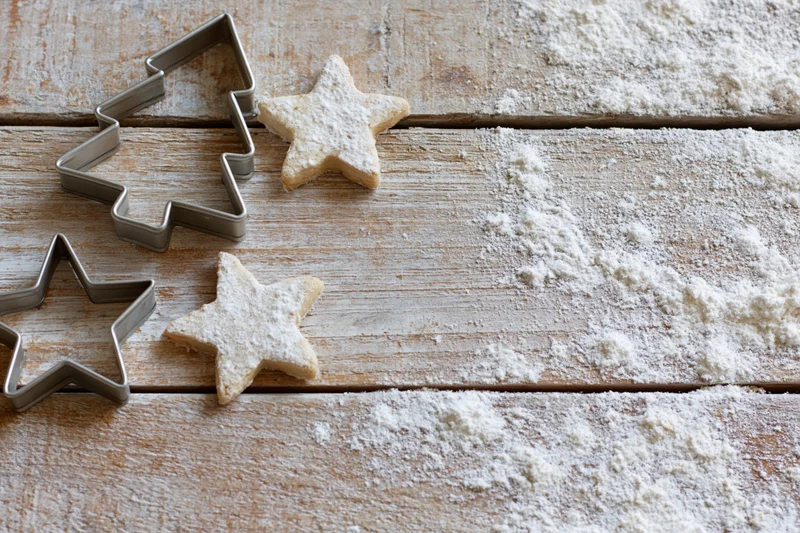 Star-shaped cookies and metal cutters on a floured wooden table