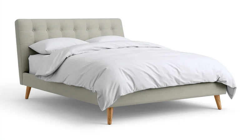 Beige tufted bed with white bedding and wooden legs on white background