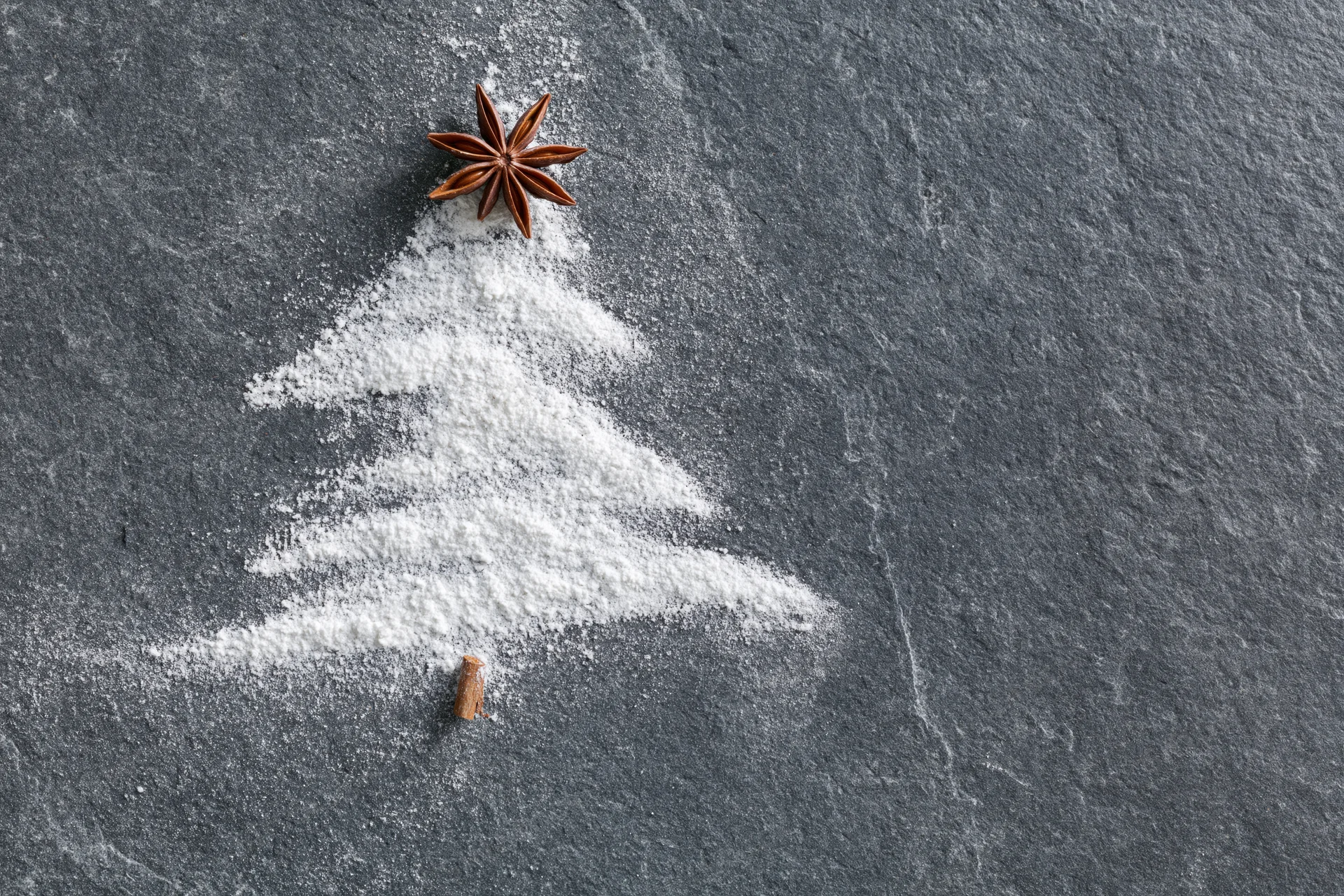 Sugar shaped as a christmas tree on slate with star anise and cinnamon stick