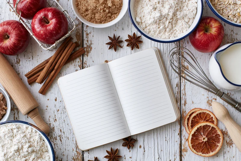 Open notebook surrounded by baking ingredients and tools on a rustic wooden table