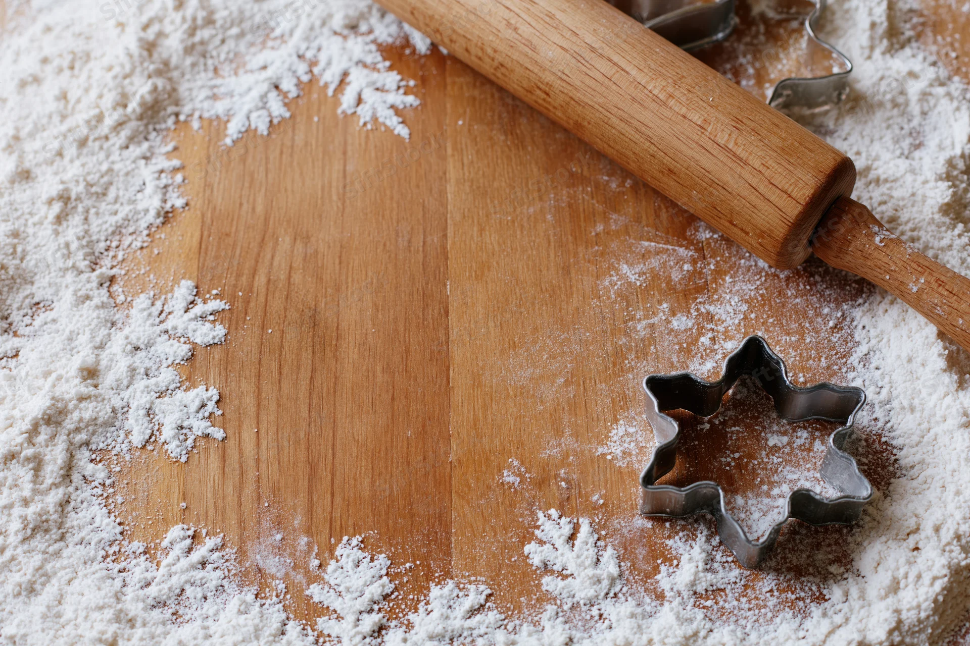 Flour-dusted wooden surface with rolling pin and star-shaped cookie cutter for holiday baking