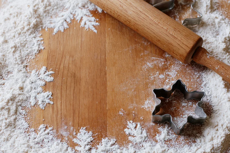 Flour-dusted wooden surface with rolling pin and star-shaped cookie cutter for holiday baking