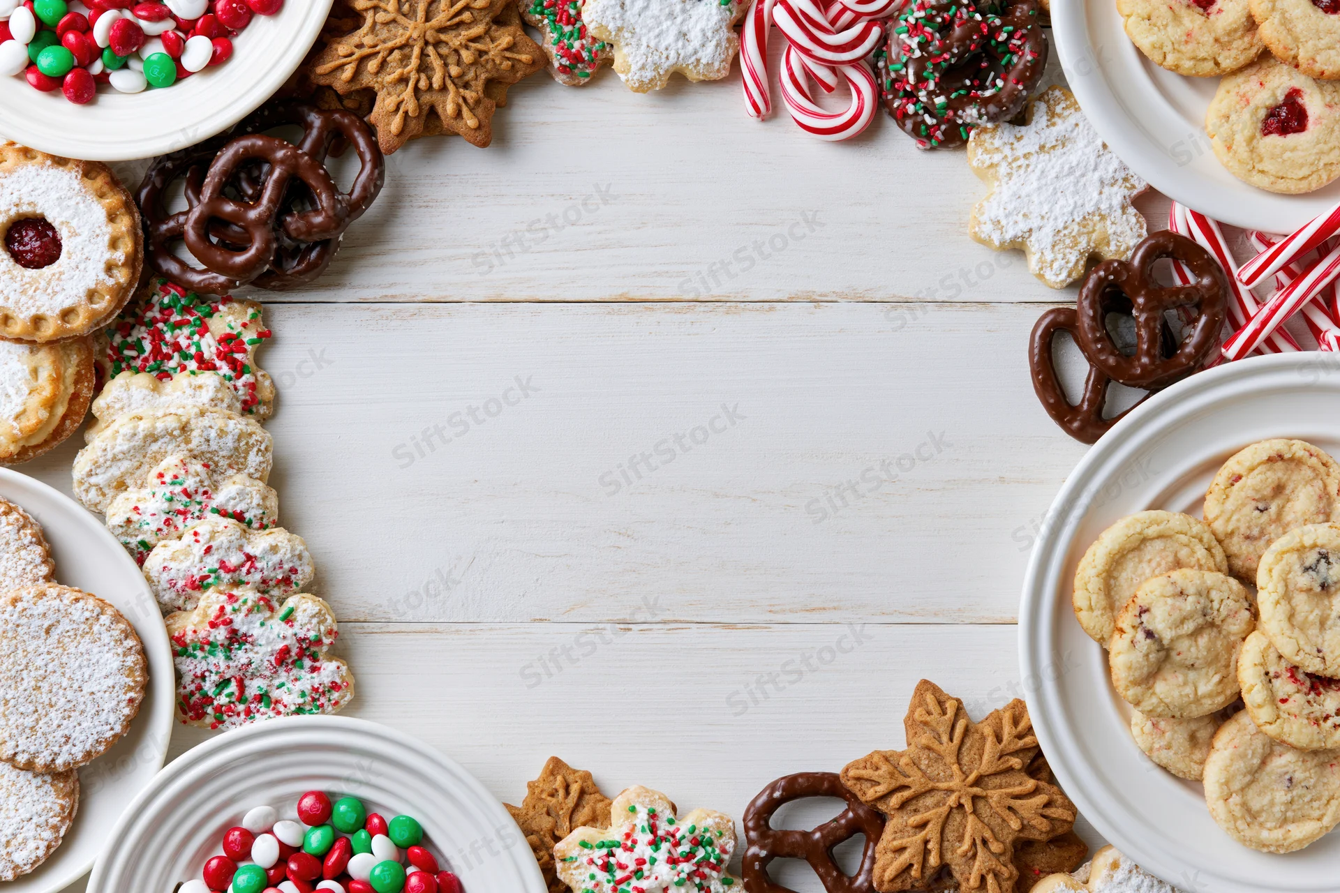 Christmas cookies and candies arranged around a white wooden table with copyspace in center