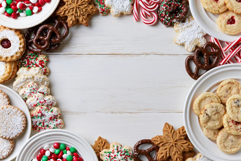 Christmas cookies and candies arranged around a white wooden table with copyspace in center