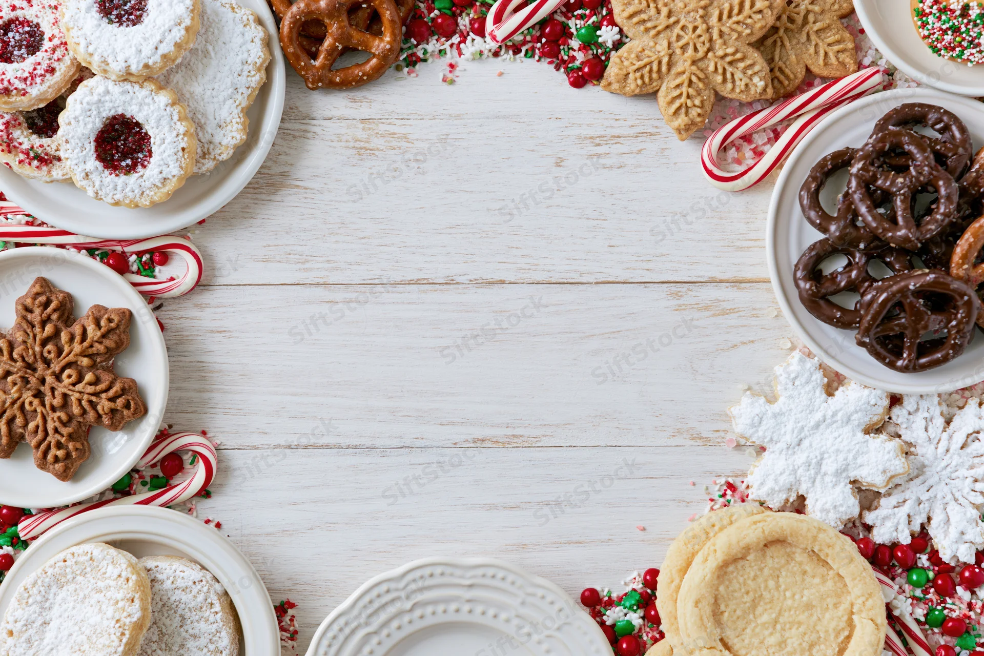 Christmas cookies and candy arranged around a white wooden table with copyspace in center