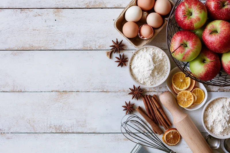 Baking ingredients arranged on a white wooden countertop with copyspace on the left