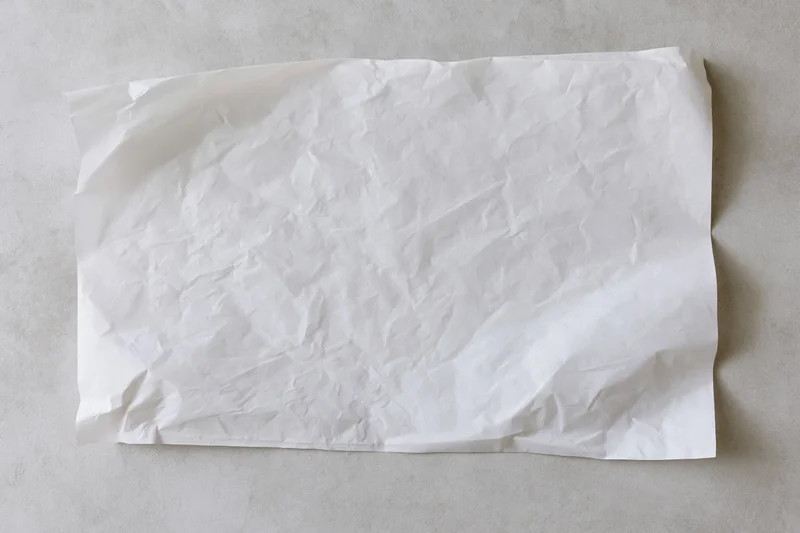 Crumpled white paper sheet lying flat on a gray concrete surface