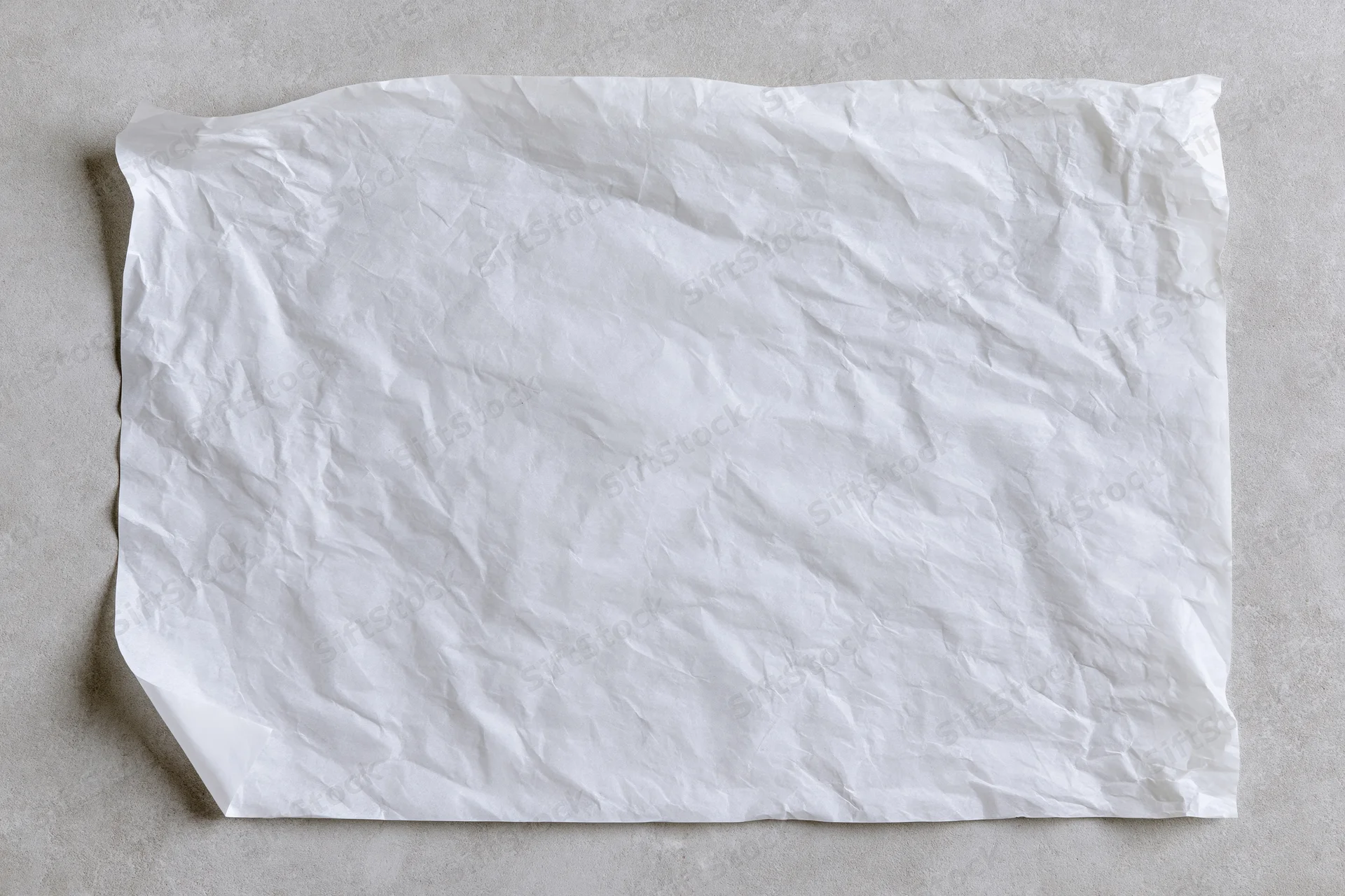 Crumpled white paper sheet lying flat on a gray surface