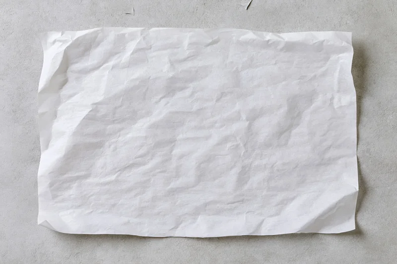 Crumpled white paper sheet lying flat on a gray concrete surface
