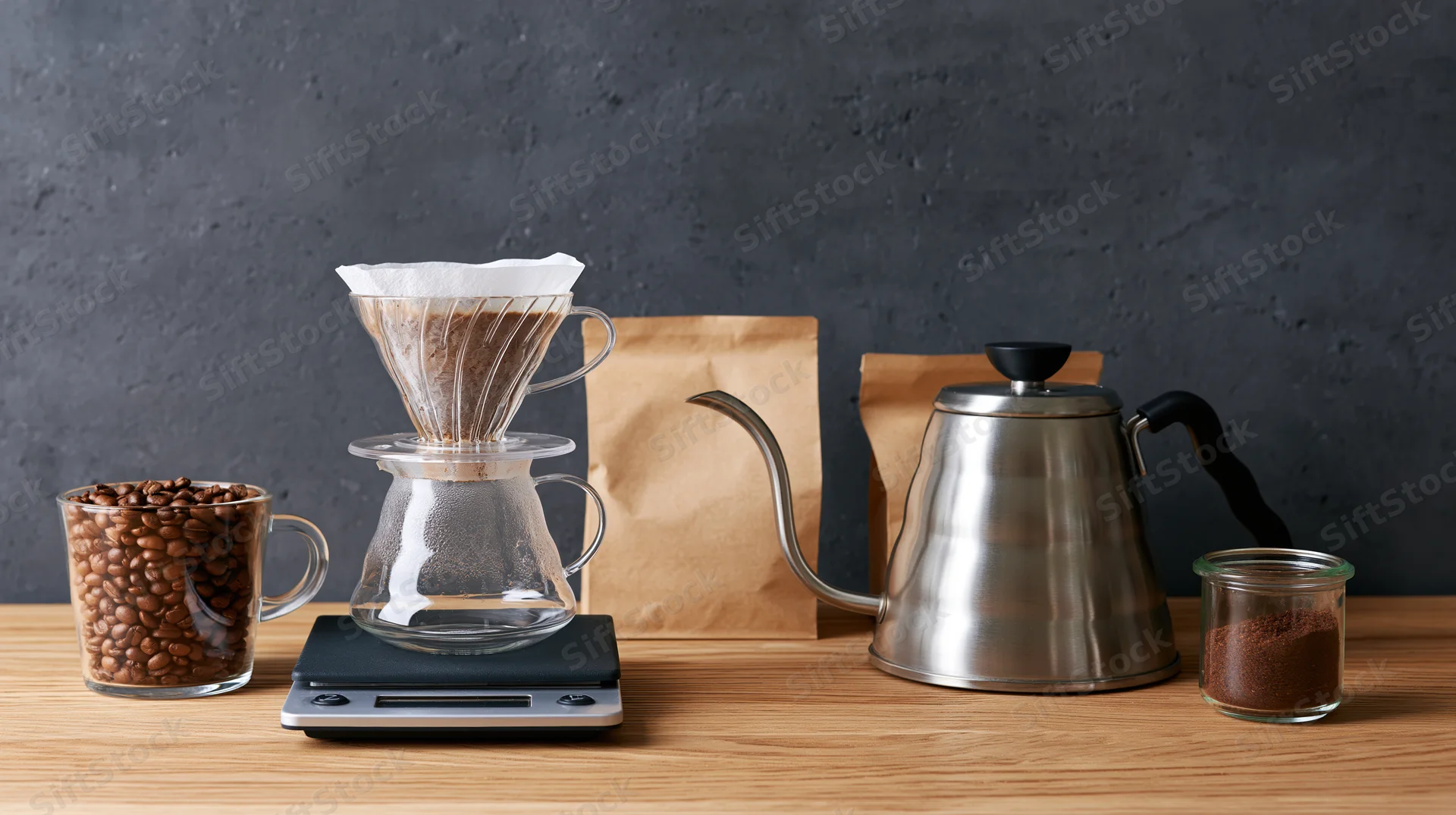 Coffee brewing setup with pour over filter, gooseneck kettle, and scale on wooden countertop