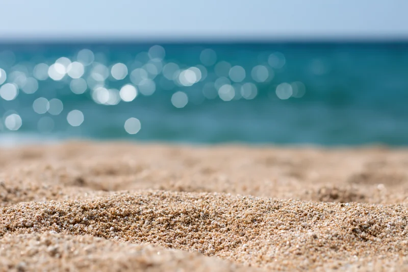 Closeup of textured sand on a beach with sparkling ocean in the background