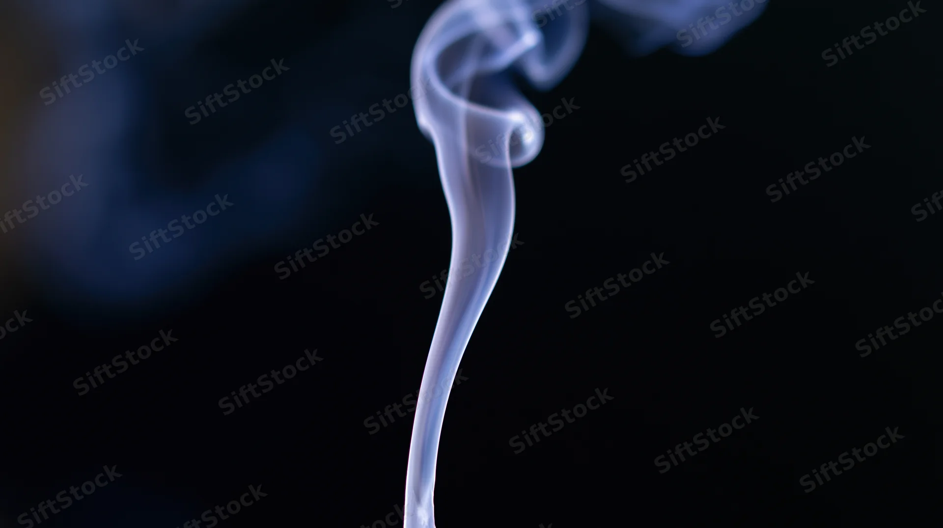 Wispy smoke rising in a dark space