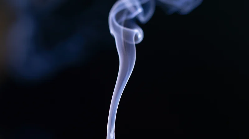 Wispy smoke rising in a dark space