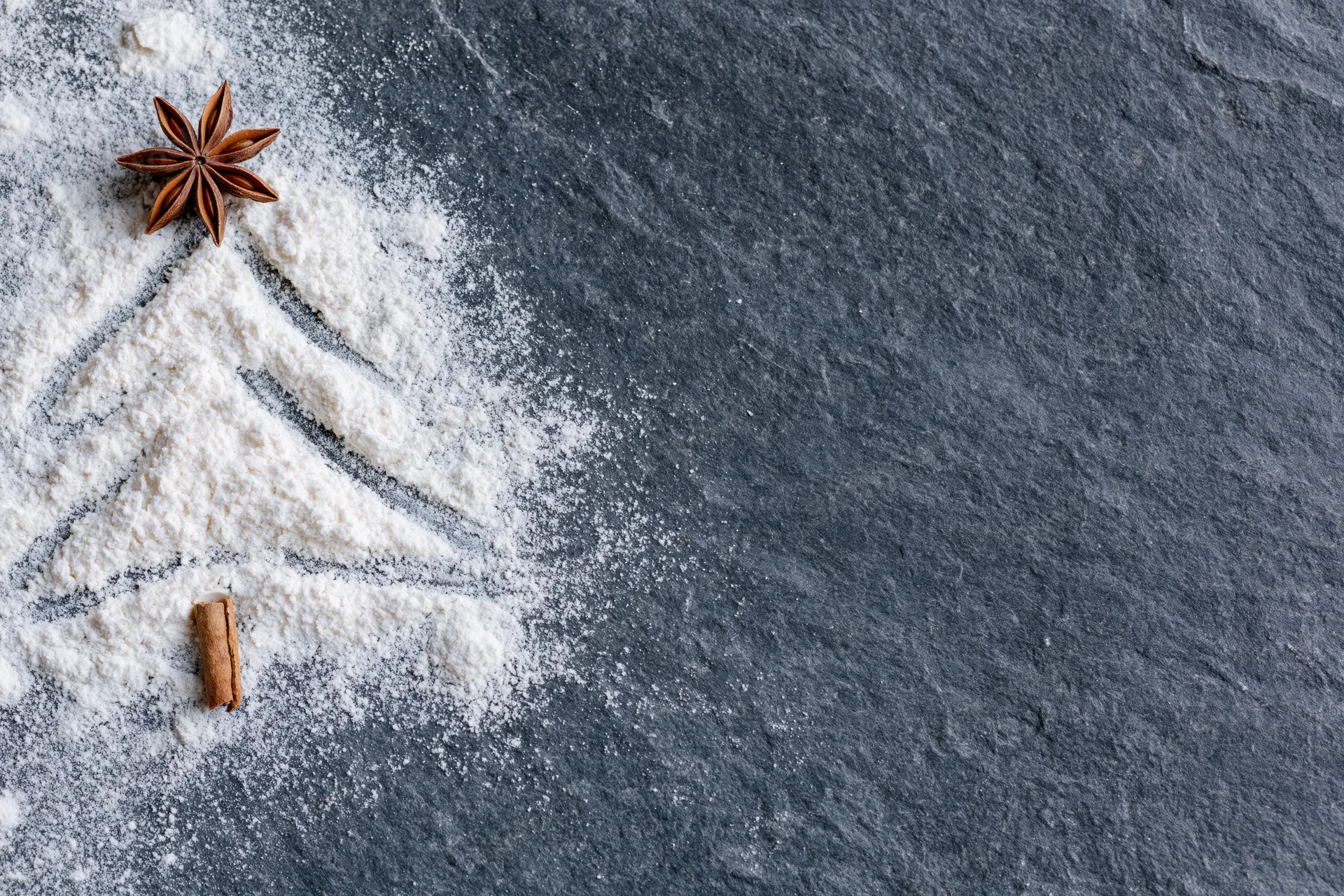 Cinnamon stick and star anise on flour dusted slate surface with copyspace