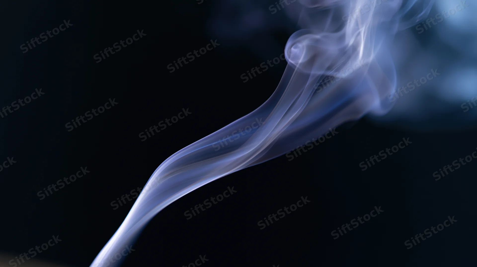 Wispy white smoke curling upward against a dark background