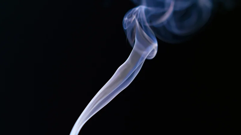 Wispy smoke rising in a dark background