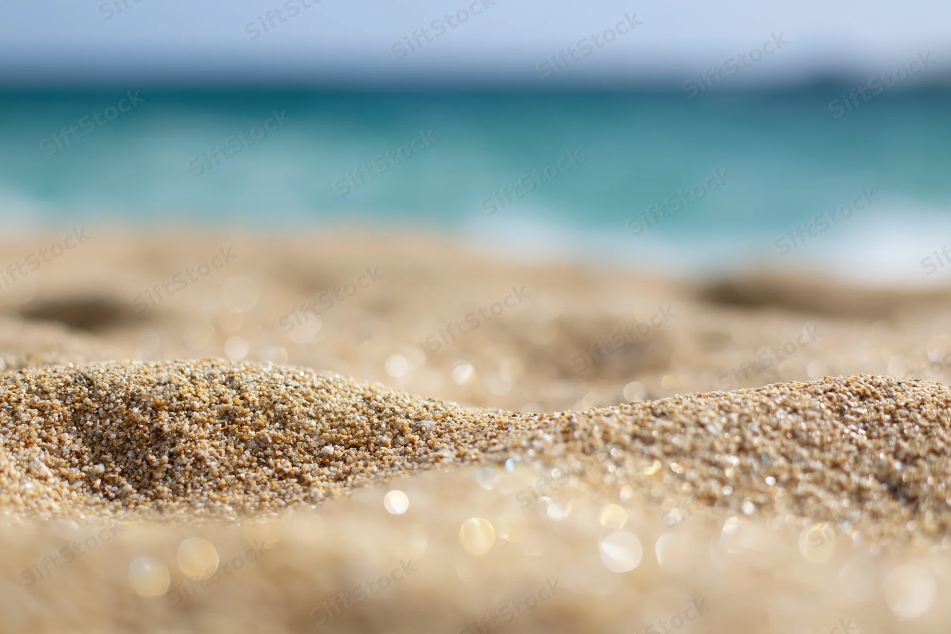 Closeup of textured sand on a beach with ocean waves in the background