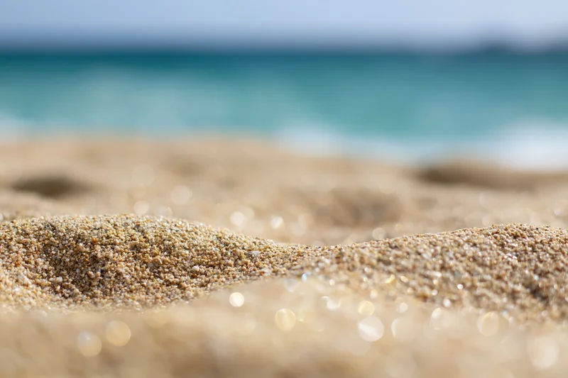 Closeup of textured sand on a beach with ocean waves in the background