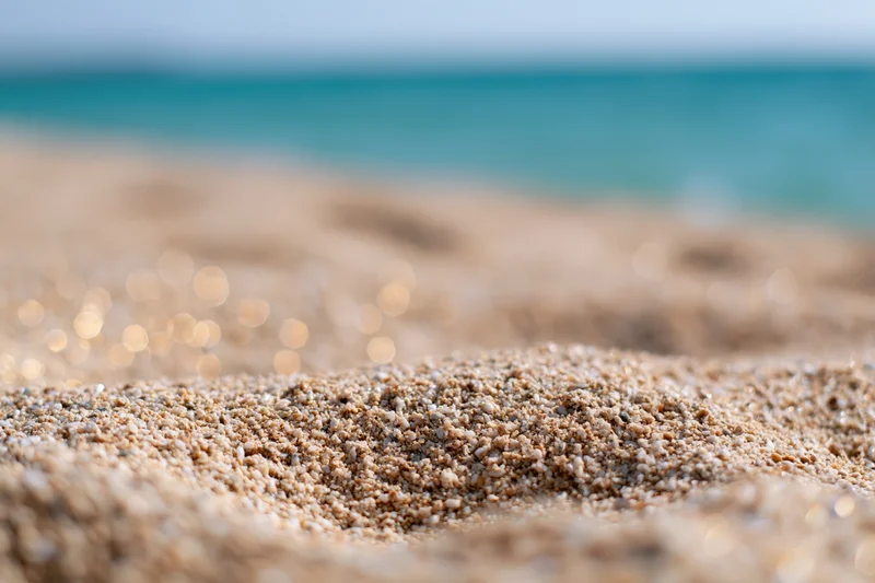 Closeup of textured sand on a beach with ocean in the background