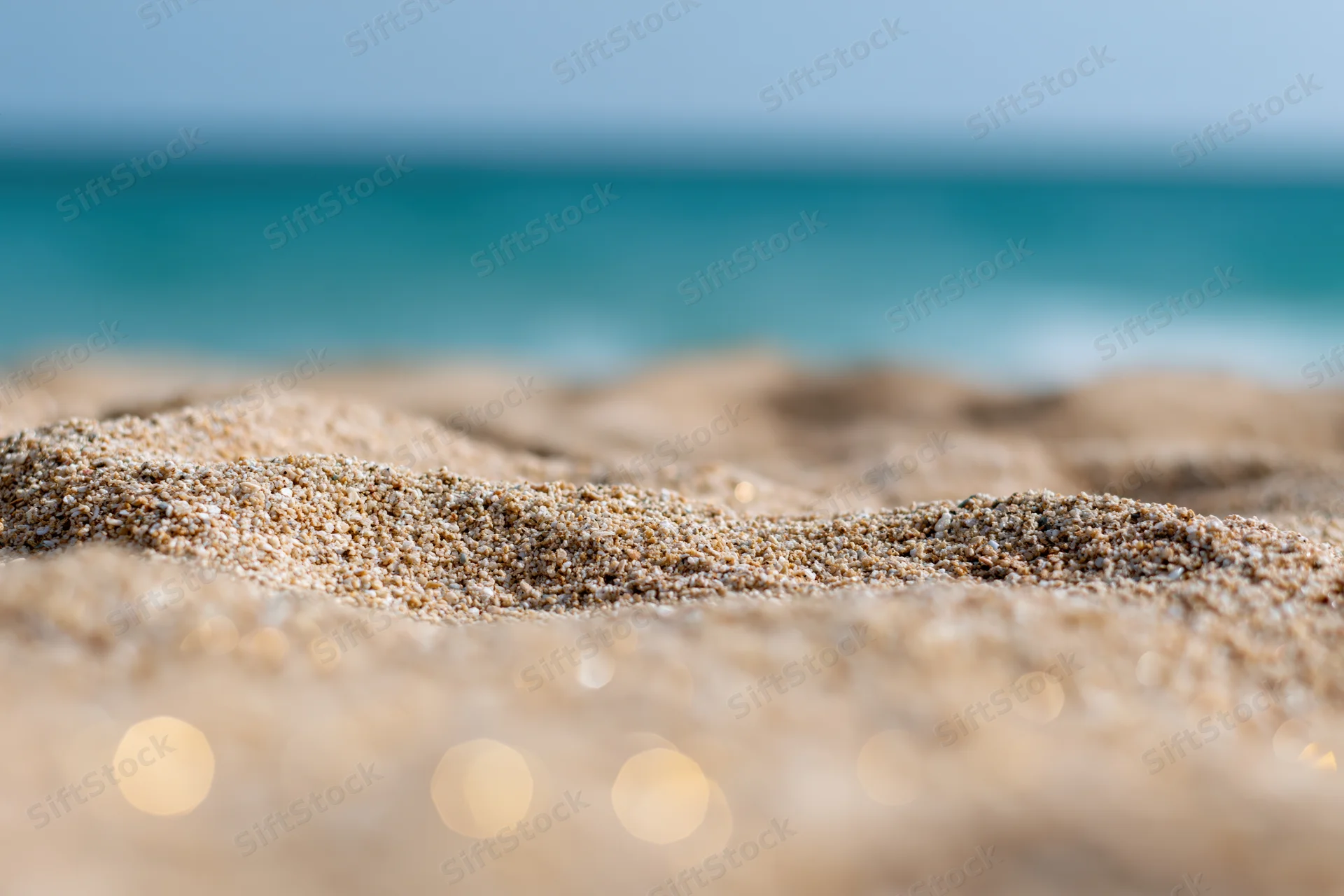 Closeup of textured sand on a beach with ocean in the background
