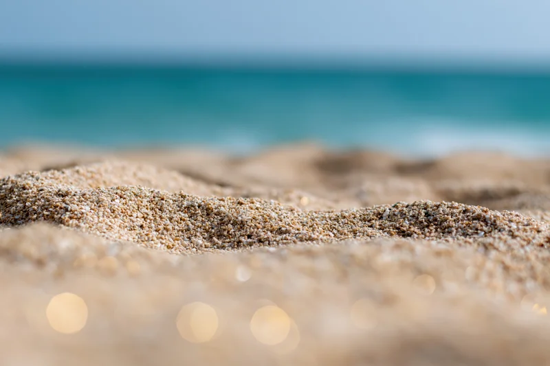 Closeup of textured sand on a beach with ocean in the background