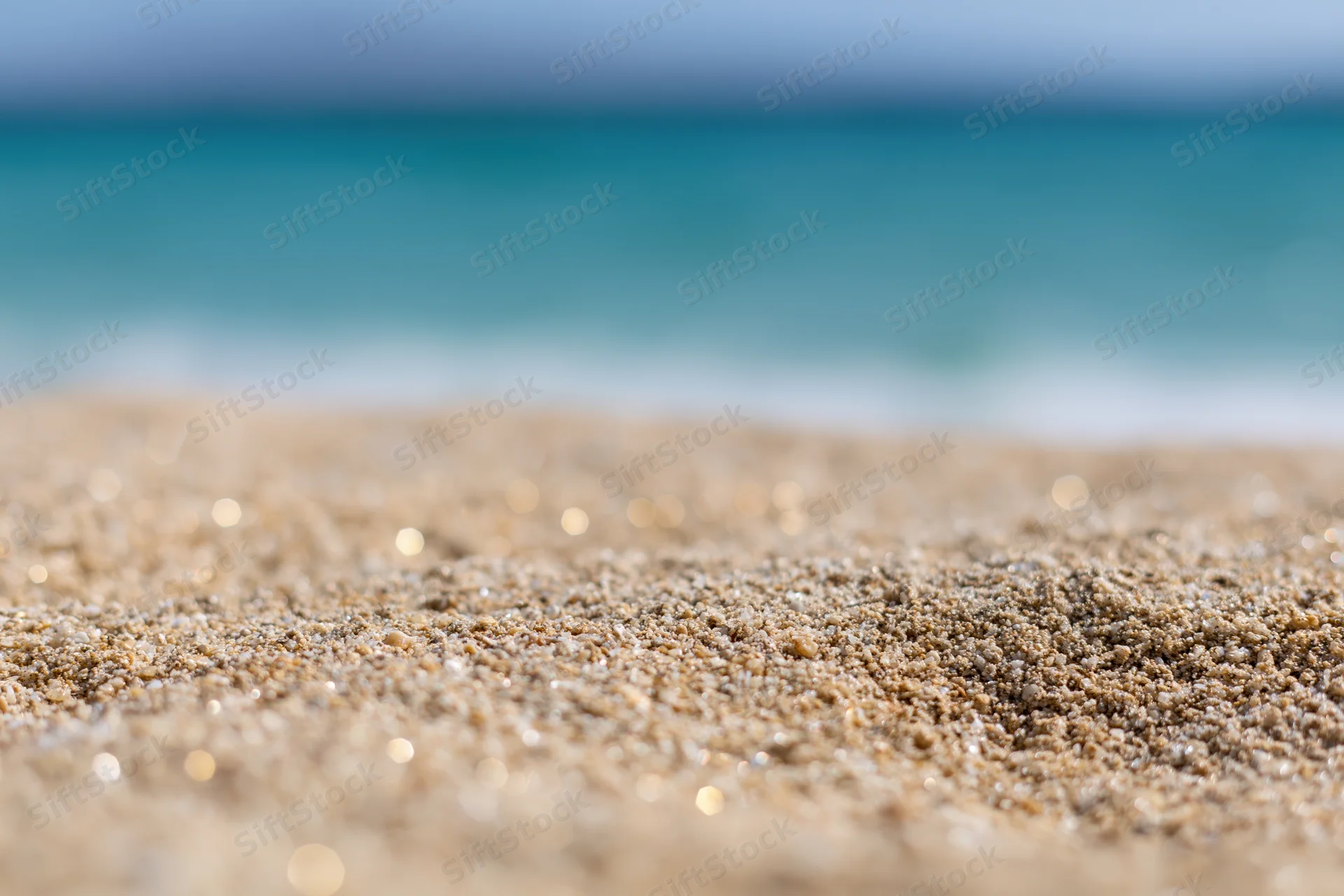 Close-up of wet sand on a beach with ocean in the background