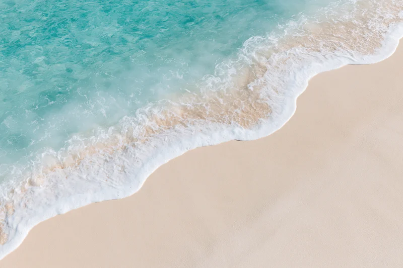 Waves rolling onto a sandy beach from above
