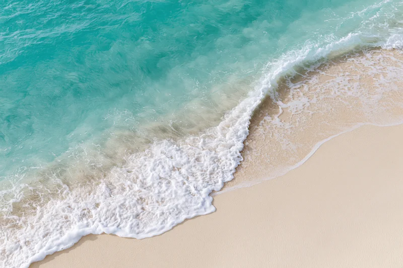 Turquoise ocean wave breaking onto sandy beach