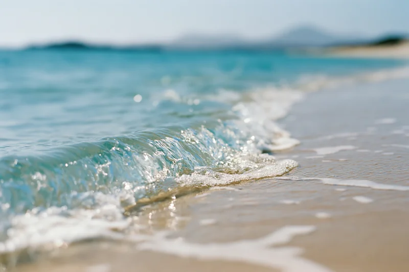 Gentle wave breaking onto sandy beach under clear sky