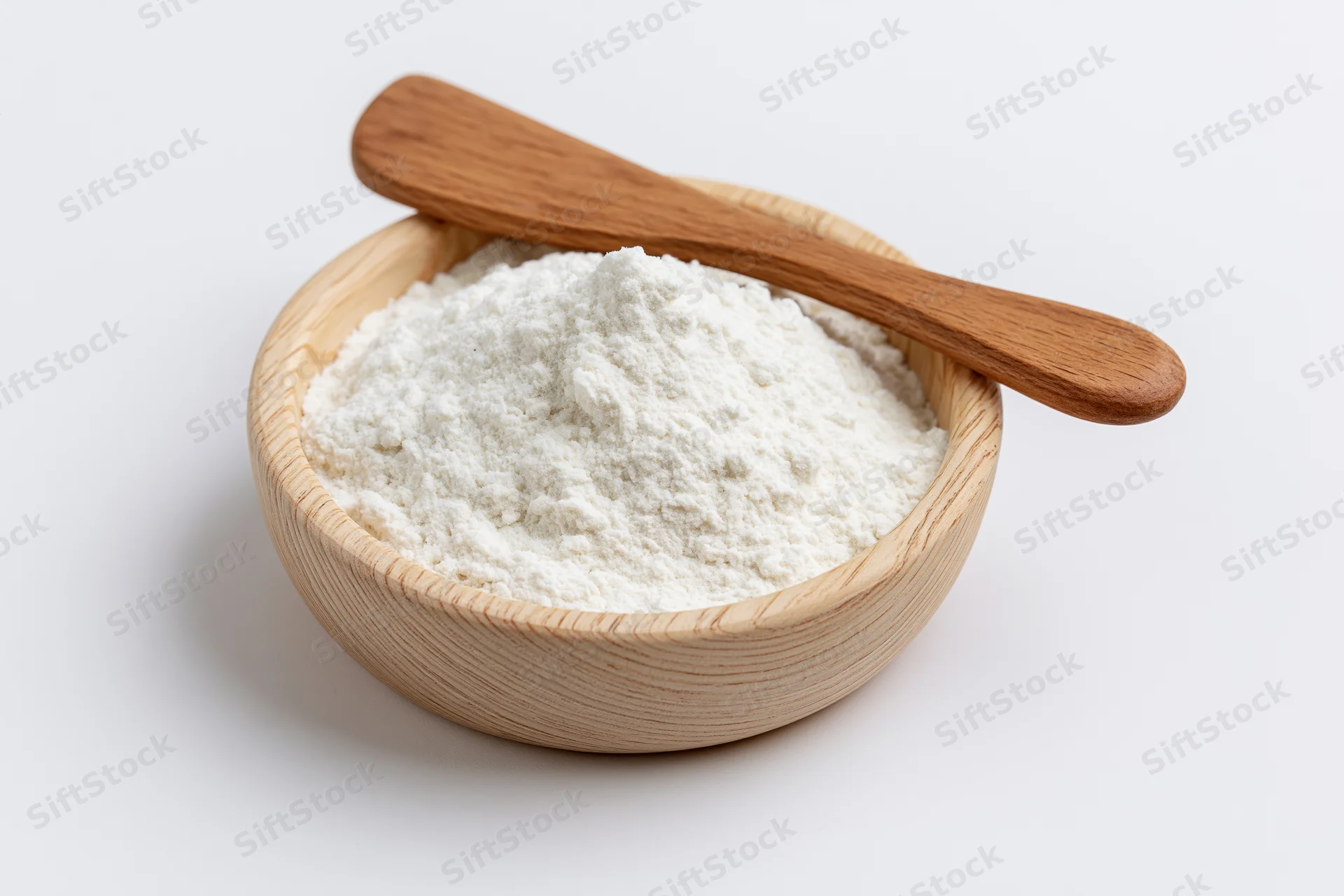 White flour in a wooden bowl with a spoon on a plain background