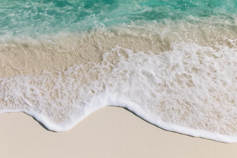 Turquoise ocean waves breaking onto white sandy beach