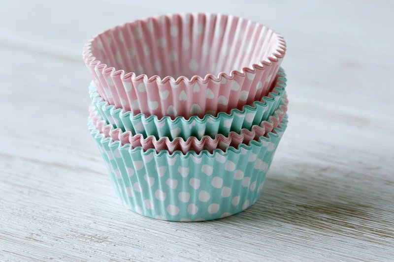 Stack of pink and mint polka dot cupcake liners on a white wooden table