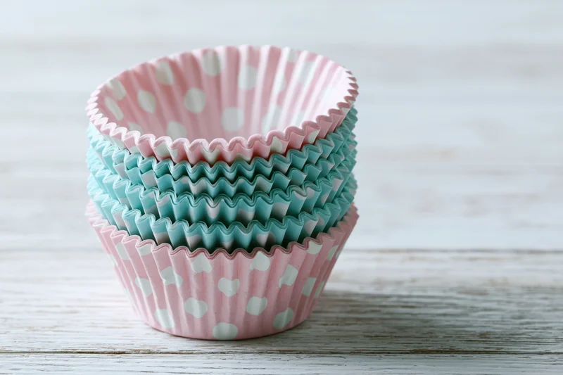 Stack of pink and blue polka dot cupcake liners on a white wooden table
