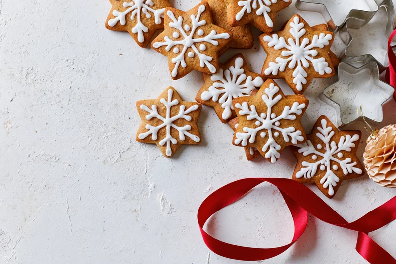 Star-shaped gingerbread cookies with white icing and red ribbon on textured white surface