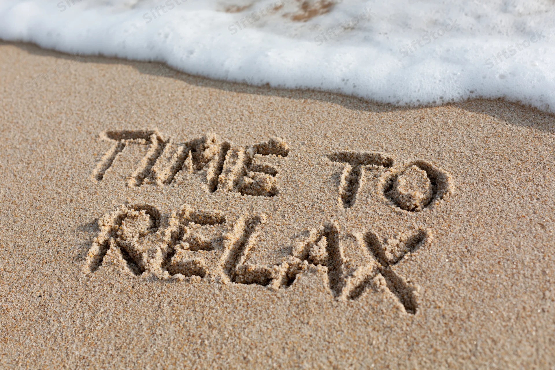 Words time to relax written in sand at beach with wave approaching