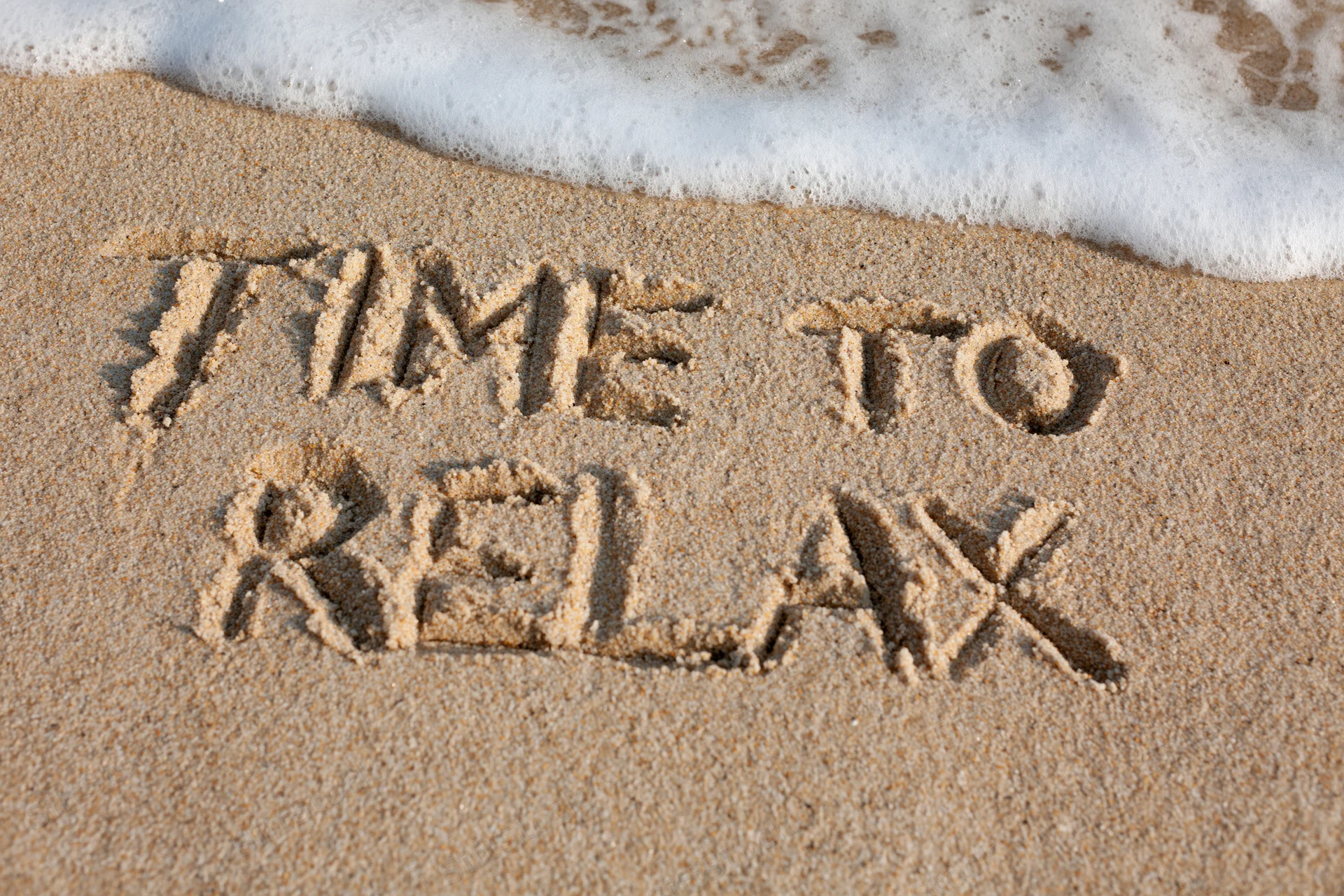 Words time to relax written in sand at beach with wave approaching