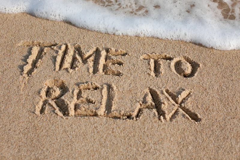 Words time to relax written in sand at beach with wave approaching