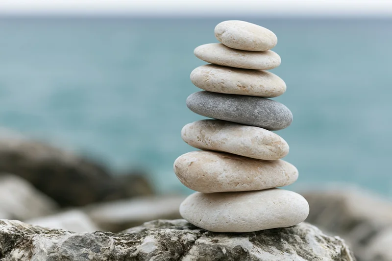Stack of smooth stones balanced on a rock by the ocean